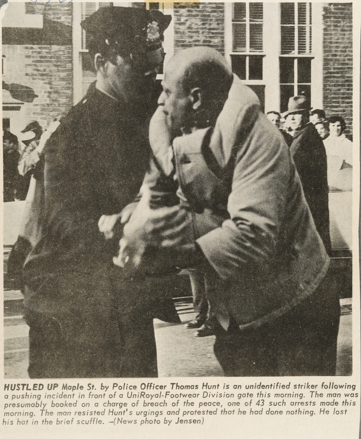 HUSTLED UP Maple St. by Police Officer Thomas Hunt is an unidentified striker following a pushing incident in front of a Unioyal-Footwear Division gate this morning. The man was presumably booked on a charge of breach of the peace, one of 43 such arrests made this morning. The man resisted Hunt's urgings and protested that he had done nothing. He lost his hat in the brief scuffle.