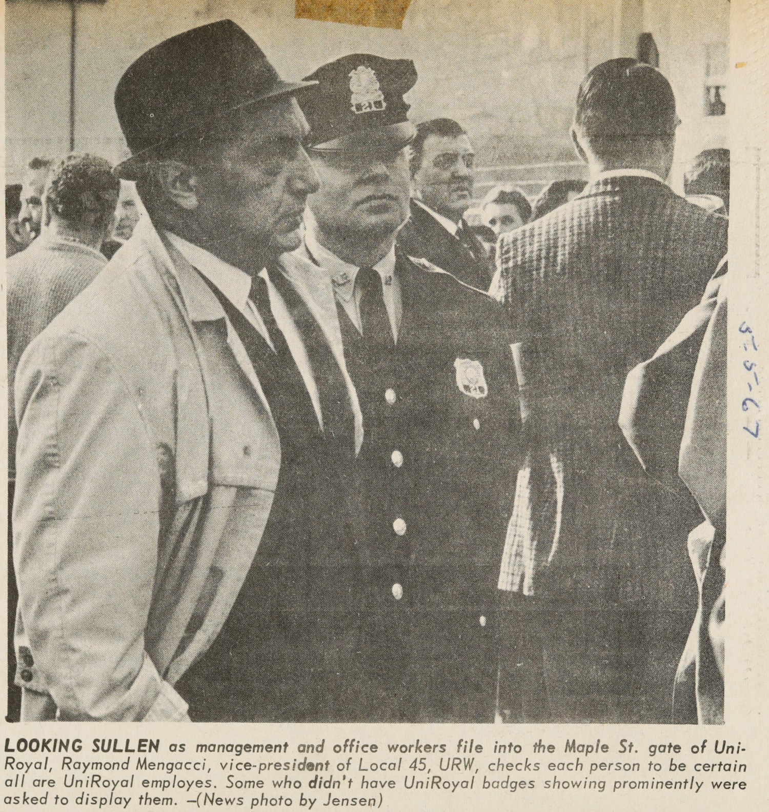 LOOKING SULLEN as management and office workers file into the Maple St. gate of UniRoyal Raymond Memorial, vice-president of Local 45, URW, checks each person to be certain all are UniRoyal employees. Some who didn't have UniRoyal badges shown prominently were asked to display them.